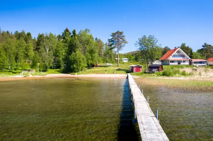 Vy över brygga med bostad till höger i bild.